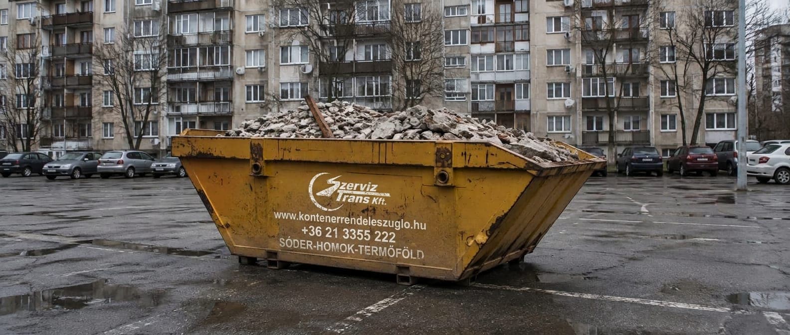 Sárga konténer egy zuglói panelház parkolójában, építési törmelékkel megrakva — sittszállítás a XIV. kerületben